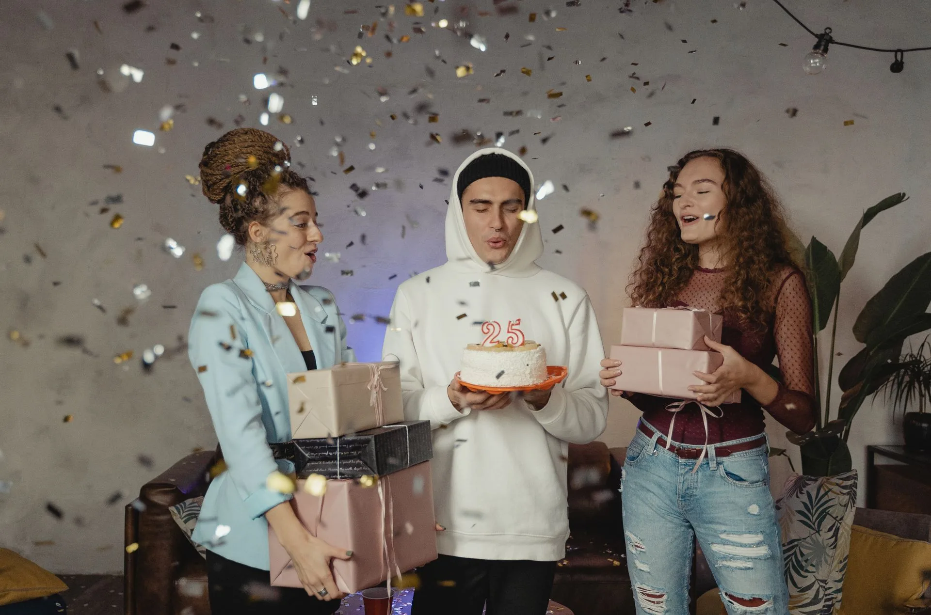 Trois amis célèbrent un anniversaire avec des cadeaux et un gâteau.