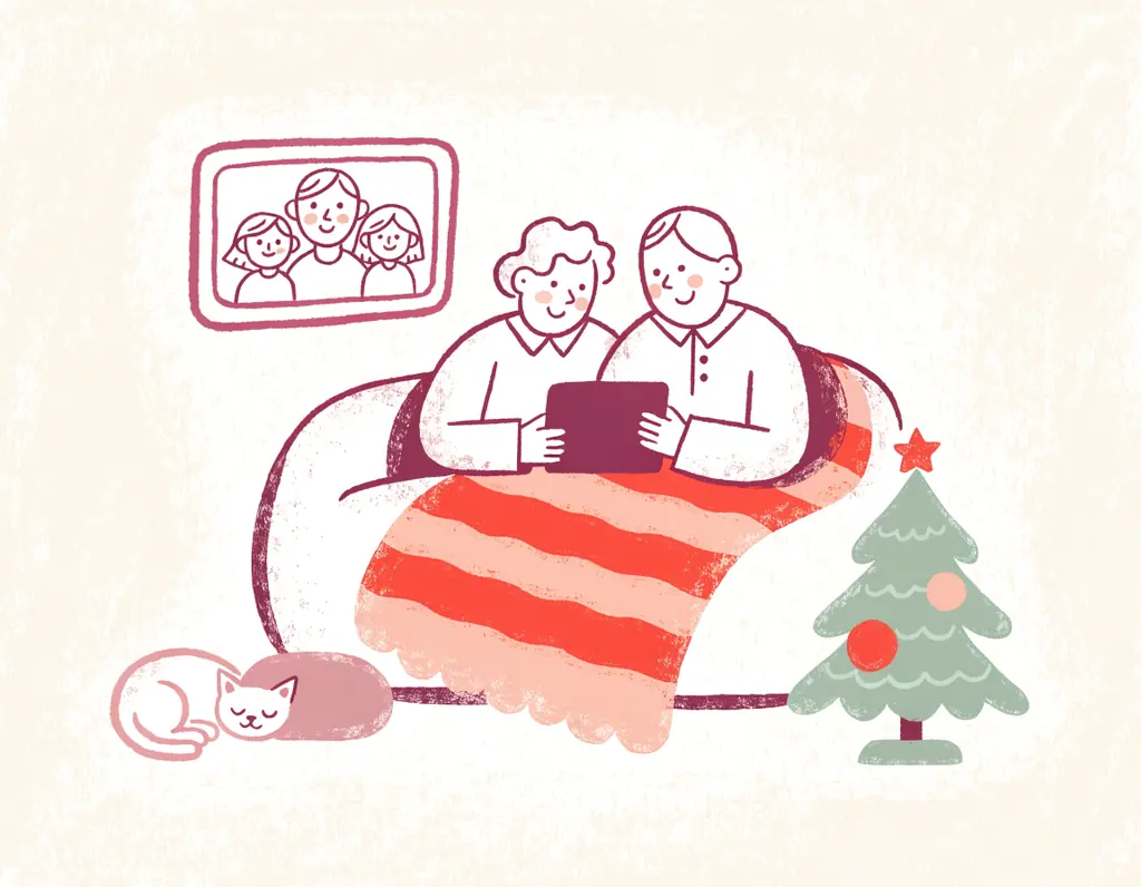 Des grands-parents souriants regardent ensemble une tablette sur leur canapé, un chat à côté d'eux et un petit sapin décoré