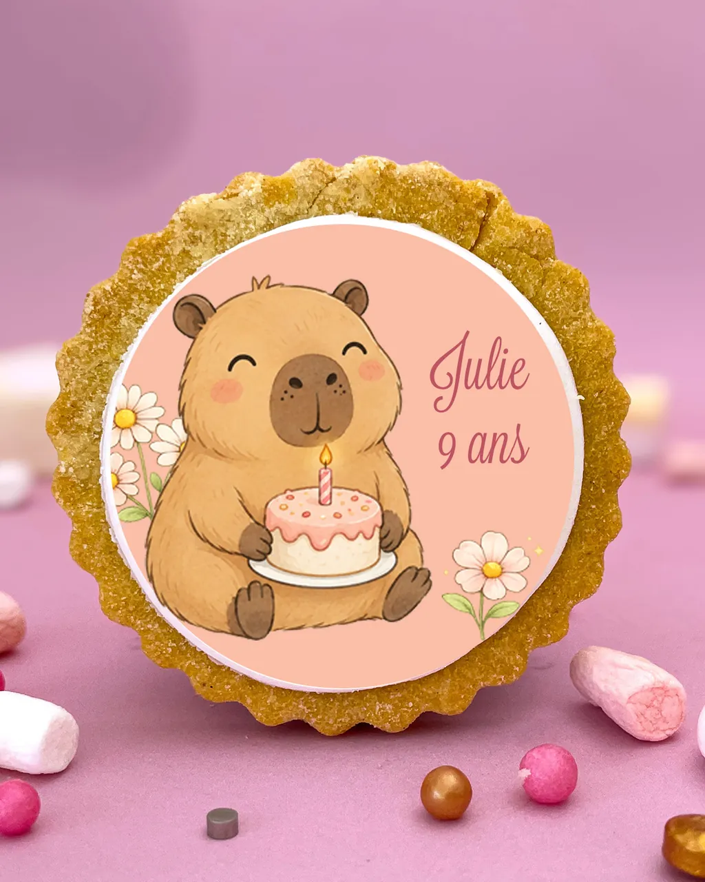 Un sablé décoré d’un capybara qui tient un gâteau d’anniversaire, au prénom « Julie » et « 9 ans »