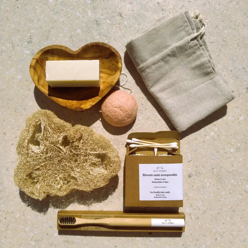 Un kit salle de bain zéro déchet : savon sur un porte-savon en bois en forme de cœur, éponge konjac, éponge loofah, brosse à dents en bambou et pochon en coton